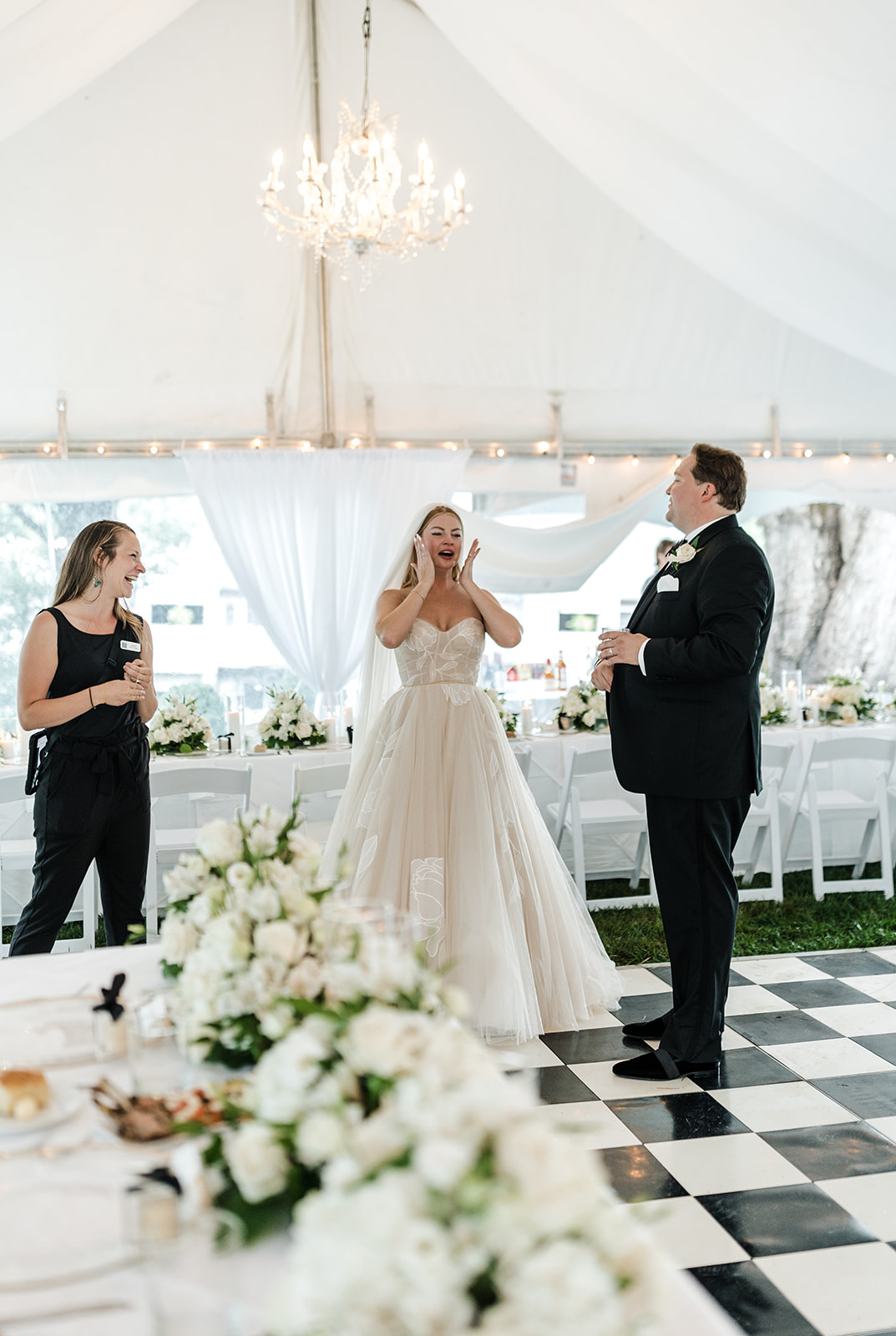 A bride and grooming standing inside a wedding reception tent, at the Greystone Inn at Lake Toxaway, North Carolina, with amazed looks on their faces as they see it for the first time.  